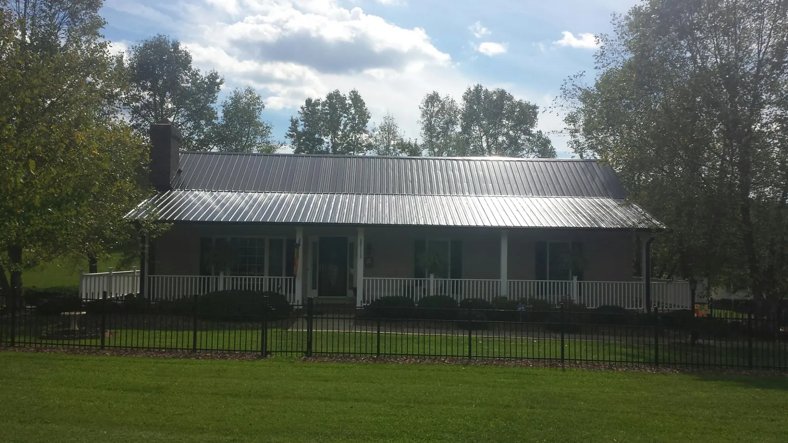 Gray metal roof on a brick ranch with a full width front porch — Gutter Guard Installation work by our crew in Mc Donald